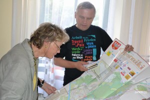 Dwóch wolontariuszy studiuje mapę w czasie wolontariatu, ubrany w koszulkę z hasłami o pokoju.