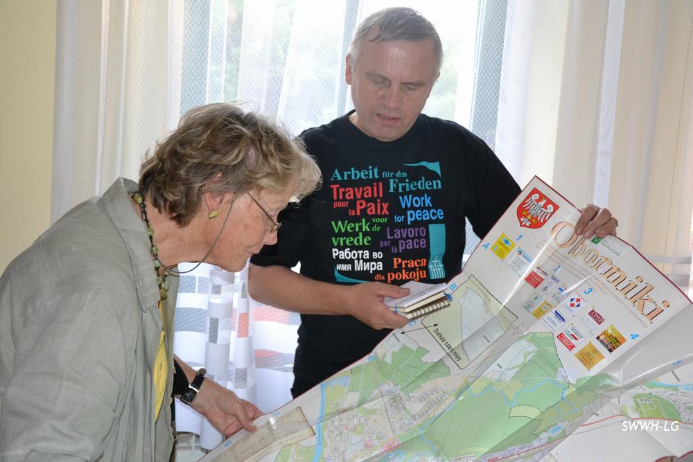 Dwóch wolontariuszy studiuje mapę w czasie wolontariatu, ubrany w koszulkę z hasłami o pokoju.