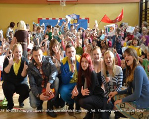 Grupa osób w sali gimnastycznej, otoczona przez dzieci, podczas wizyty Drużyny Libera w obornickich szkołach, 25.10.2012.