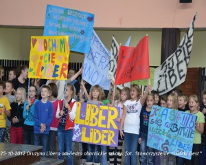 Grupa dzieci trzyma transparenty z hasłami podczas wizyty Drużyny Libera w obornickiej szkole, 25-10-2012.