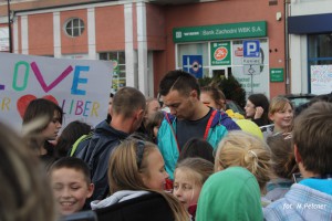 Uczestnicy trzymają transparent z napisem „LOVE = LIBER” na tle budynku z bankiem.
