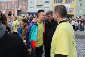 Uczestnicy wydarzenia w centrum miasta, w tle budynki i tłum ludzi.