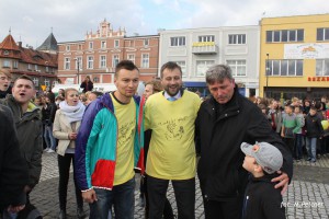Czterej mężczyźni z chłopcem stoją na placu, w tle budynki i tłum ludzi, galeria Liber 2012.