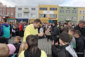 Tłum ludzi zgromadził się na placu miejskim, w centrum wydarzenia stoi mężczyzna w żółtej koszuli.