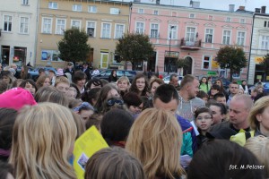 Tłum ludzi zgromadzony na placu przed budynkami.