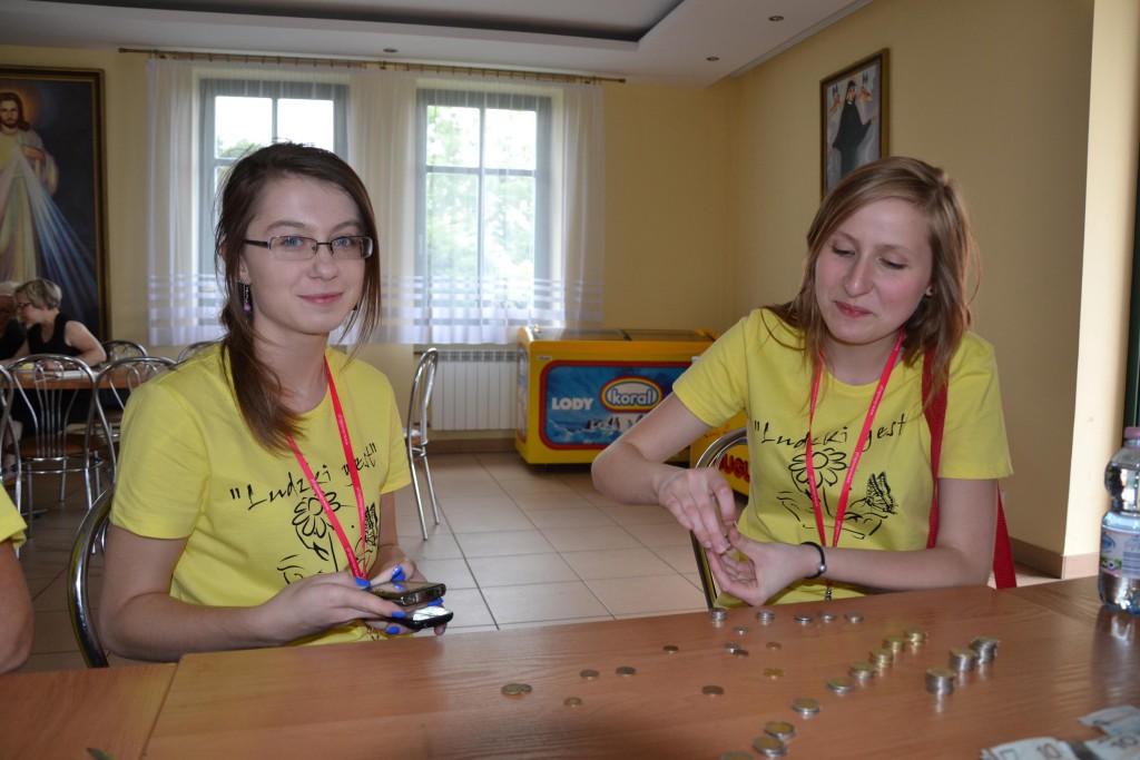 Dwie osoby układają monety na stole podczas wydarzenia w fundacji hospicyjnej, rok 2012.