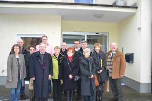 Grupa osób stoi przed wejściem do budynku.