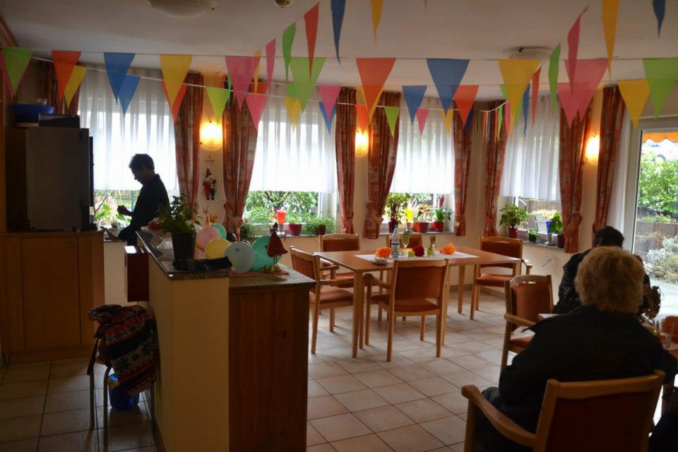 Sala z dekoracjami w stylu festiwalowym, stoły z nakrytymi stolikami i osoby siedzące przy nich.