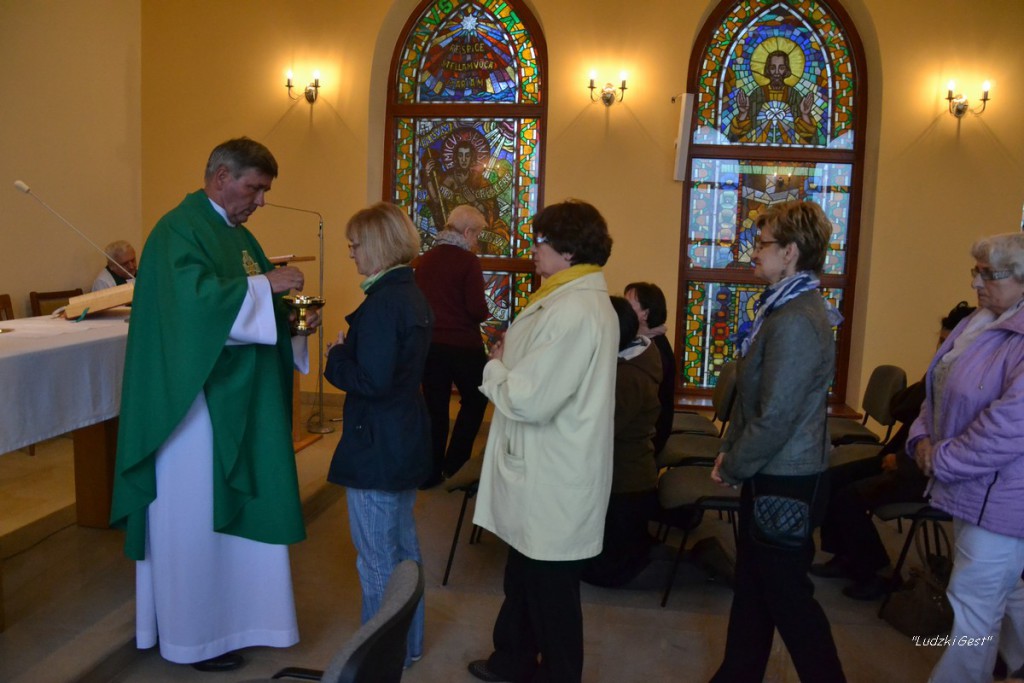 Uroczystość religijna w kościele: kapłan udziela błogosławieństwa wiernym w obecności witraży.