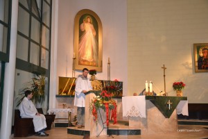 Scena z nabożeństwa w kaplicy: mężczyzna odprawia mszę, a osoba siedzi na ławce w pobliżu ołtarza.