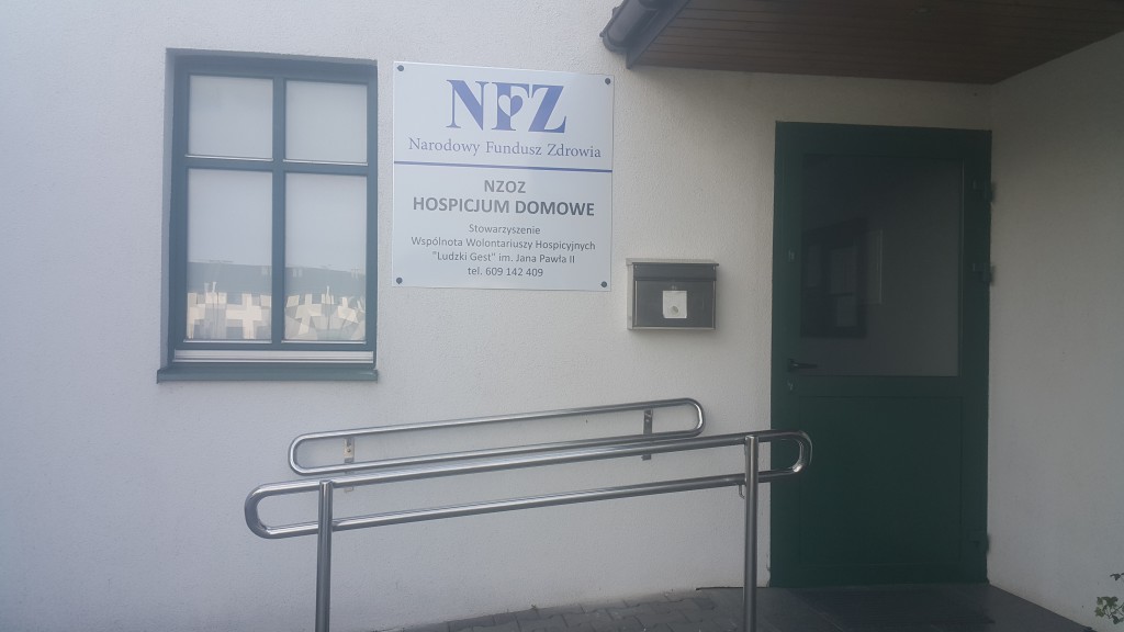 Tablica informacyjna Hospicjum Domowego „Ludzki Gest” na budynku siedziby przy ul. Droga Leśna 60
